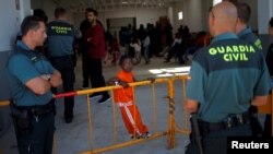 Spanish Civil Guards guard the entrance of a makeshift emergency building where migrants, intercepted aboard dinghies off the coast in the Strait of Gibraltar, rest after arriving on a rescue boat at the port of Barbate, southern Spain, July 28, 2018. 