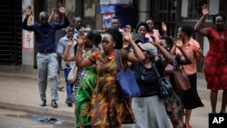 Residents are ordered out of a building with their hands in the air as security forces pursue protesters in Kampala, Uganda, Aug. 20, 2018.