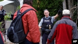 FILE - Royal Canadian Mounted Police greet migrants as they enter into Canada at an unofficial border crossing at Champlain, N.Y., Aug. 7, 2017. A Canadian court on July 22, 2020, invalidated the country's Safe Third Country Agreement with the U.S.