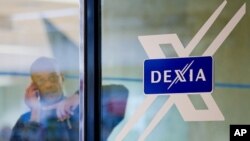 A man looks out of a door next to the Dexia logo at the corporate headquarters in Brussels, October 4, 2011.