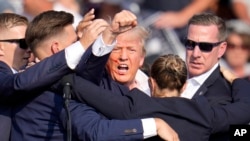 Kandidat presiden dari Partai Republik, mantan Presiden Donald Trump, dibantu turun dari panggung oleh Secret Service pada acara kampanye di Butler, pada Sabtu, 13 Juli 2024. (Foto: AP)