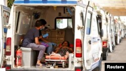 Pacientes con problemas respiratorios por COVID-19 son atendidos en ambulancias en Ahmedabad, India, mientras esperan a ser admitidos en un hospital el 28 de abril de 2021.