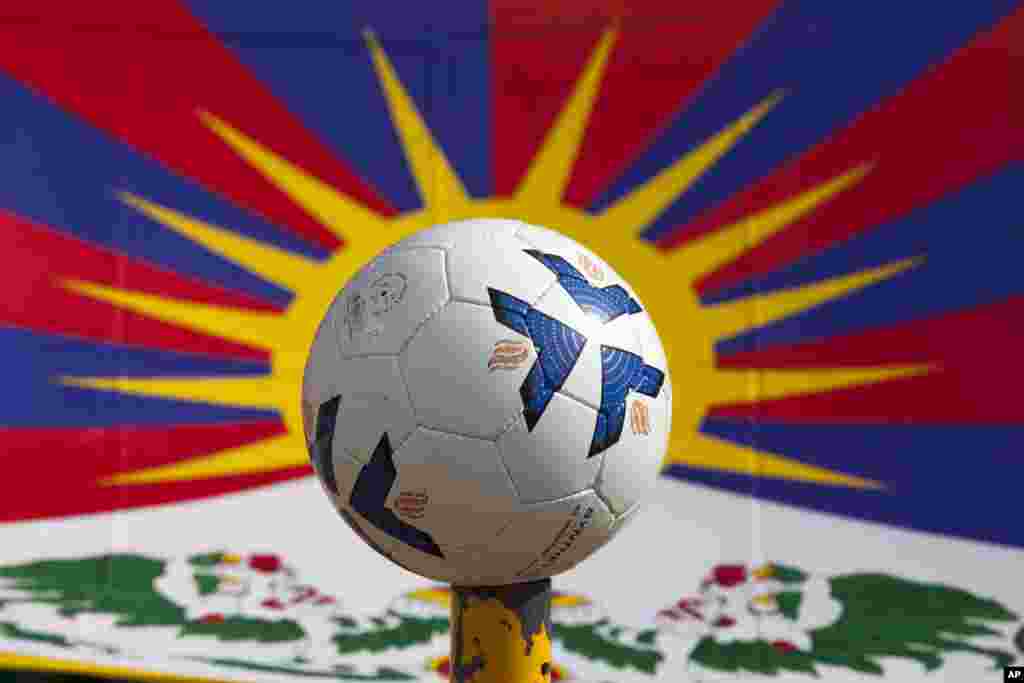 Sebuah bola di depan bendera nasional Tibet sebelum pertandingan dimulai di Dharmsala, India, Minggu, 10 Juni 2018. Para penggemar sepak bola seluruh dunia mulai bersiap menonton Piala Dunia 2018. (Foto:AP)