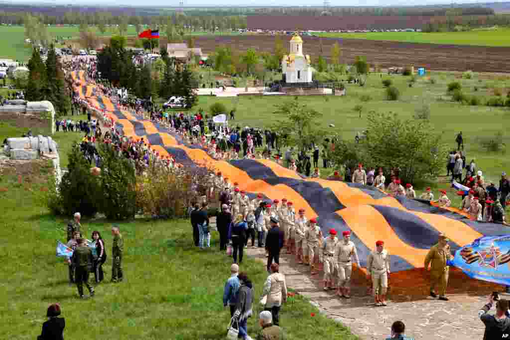 Activists carry a 300-meter-long St. George ribbon, which has become a symbol of the pro-Russian insurgency in eastern Ukraine, during celebrations of the Victory Day at a World War II memorial in Saur-Mogila, east of Donetsk, May 8, 2021.