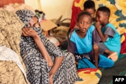 FILE - A woman and children sit with other people displaced by conflict at a mosque in Sudan's northern border town of Wadi Halfa near Egypt on September 12, 2023.