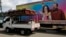 A truck carrying coffins drives past a banner of Nicaragua's President -- and presidential candidate -- Daniel Ortega and his wife and running mate, Rosario Murillo, on a mobile clinic, in Masaya, Nov. 2, 2021.