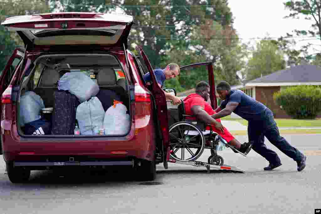 Lake Charles Fire Department personnel Alvin Taylor, right, and Jeremy Harris, left, assist Tim Williams into a transport van as he evacuates Lake Charles, La., Aug. 26, 2020.