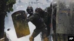 Guardias bolivarianos se defienden del lanzamiento de una lata con materia fecal lanzada contra ellos por manifestantes opositores al régimen.