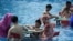 People play mahjong as they sit in water at a water park on a hot day in Chongqing, China August 2, 2017. 