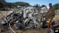 FILE - A Somali soldier stands near a vehicle destroyed by a suicide car bomb attack south of Mogadishu, Somalia — an attack that followed the killing of al-Shabab's top leader in a U.S. airstrike, Sept. 8, 2014. 