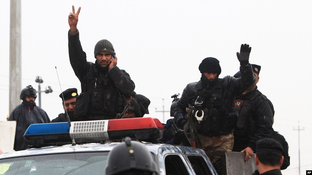 An Iraqi riot police officer flashes the V-sign as his unit returns to its headquarters from clashes between Iraqi army and al-Qaida fighters Basra, Iraq's second-largest city, Jan. 5, 2014.
