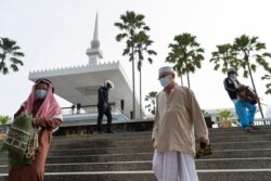 A police officer arrives to disperse Muslims praying outside the closed National Mosque to celebrate Eid al-Fitr, amid the coronavirus outbreak, in Kuala Lumpur, May 24, 2020.