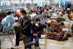 Evacuees from Afghanistan wait with other evacuees to fly to the United States or an other safe location in a makeshift departure gate inside a hangar at the U.S. airbase in Ramstein, Germany, Sept. 1, 2021.