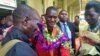 David Emong's parents wrap garlands around his neck at Entebbe International Airport, welcoming him back to Uganda after his Paralympics win. (L. Paulat/VOA)