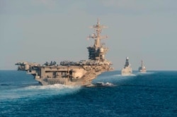 FILE - In this Nov. 19, 2019, photo made available by U.S. Navy, the aircraft carrier USS Abraham Lincoln, left, the air-defense destroyer HMS Defender and the guided-missile destroyer USS Farragut transit the Strait of Hormuz.