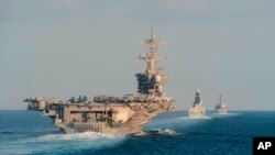 ARCHIVO - El portaaviones USS Abraham Lincoln, a la izquierda, el destructor de defensa aérea HMS Defender y el destructor de misiles guiados USS Farragut transitan por el Estrecho de Ormuz en esta fotografía del 19 de noviembre de 2019 proporcionada por la Marina de EE. UU.