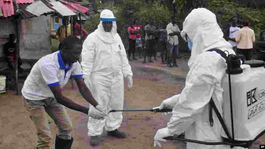 Des agents de la santé se lavent les mains après avoir prélevé l’échantillon du sang d’un malade dans le faubourg de Monrovia, Liberia, pour un test au laboratoire, le 30 juin 2015.