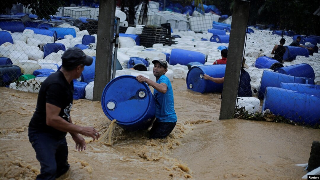 Varios hombres recuperan barriles de plástico que fueron arrastrados por una inundación provocada por lluvias de la tormenta Eta en Toyos, Honduras, el 4 de noviembre de 2020.