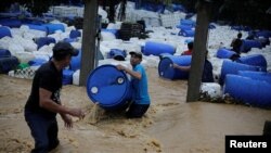 Varios hombres recuperan barriles de plástico que fueron arrastrados por una inundación provocada por lluvias de la tormenta Eta en Toyos, Honduras, el 4 de noviembre de 2020.