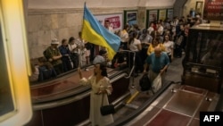 A woman waves a Ukrainian national flag as people take shelter in the Khreshchatyk metro station during an air strike alarm on Ukraine’s Independence Day in Kyiv, on August 24, 2023, amid the Russian invasion of Ukraine.