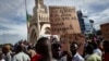 Un homme tient une pancarte alors que des partisans du CNSP participent à un rassemblement sur la place de l'Indépendance à Bamako, le 8 septembre 2020.