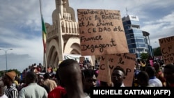 Un homme tient une pancarte alors que des partisans du CNSP participent à un rassemblement sur la place de l'Indépendance à Bamako, le 8 septembre 2020.