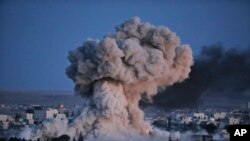 FILE - Thick smoke from an airstrike by the U.S.-led coalition rises in Kobani, Syria, as seen from a hilltop on the outskirts of Suruc, at the Turkey-Syria border, Oct. 20, 2014.