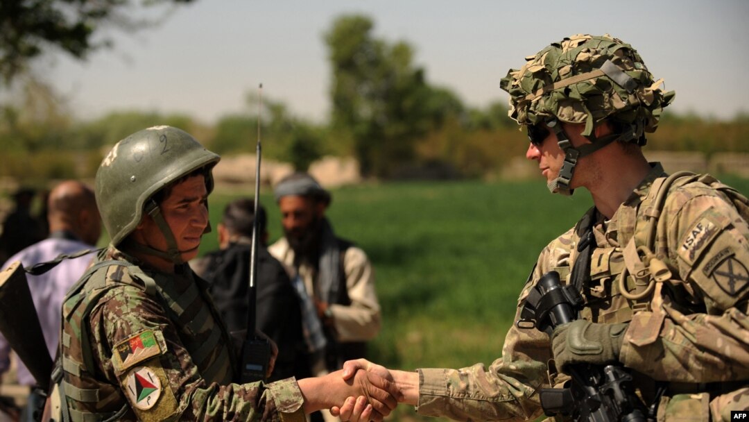 FILE - A U.S. soldier, right, shakes hands with an Afghan National Army soldier before the opening ceremony for a newly completed mosque in southern Kandahar province, April 1, 2011, where the U.S. is funding its rebuilding.