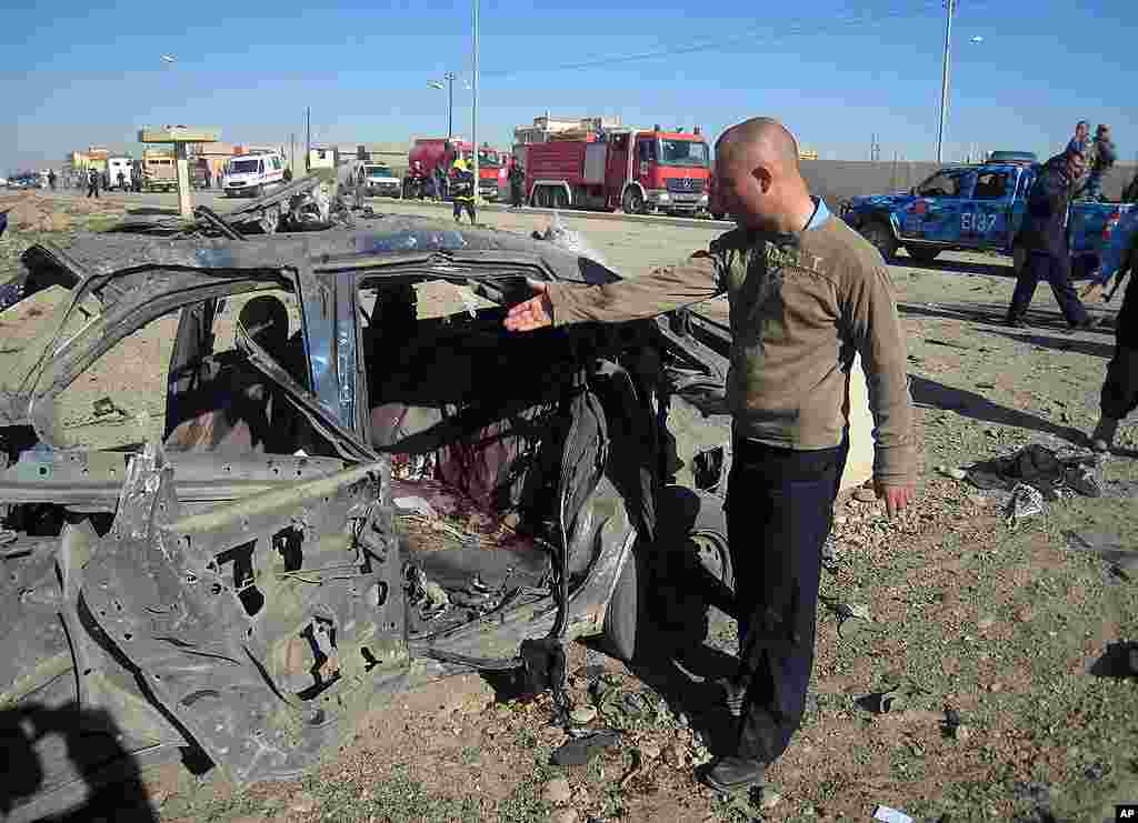 A man gestures at a destroyed vehicle at the scene of a car bomb attack in Kirkuk, north of Baghdad. (AP)