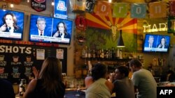 People sit behind a bar as they attend a watch party for the US Presidential debate between Vice President and Democratic presidential candidate Kamala Harris and former US President and Republican presidential candidate Donald Trump at American Eat Co. i