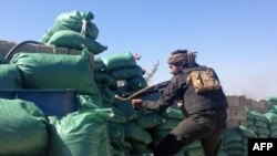 FILE - A member of the tribal groups fighting along with the Iraqi government security forces takes a position behind sandbags during clashes with jihadists in the Hosh district of Ramadi as the Islamic State jihadist group launched a coordinated attack on government-held areas of the western Iraqi city, March 11, 2015.