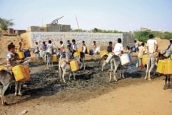 FILE - Children riding on donkeys queue to fill their jerrycans with water from a cistern at a make-shift camp for the internally displaced in Yemen's northern Hajjah province, July 12, 2021.
