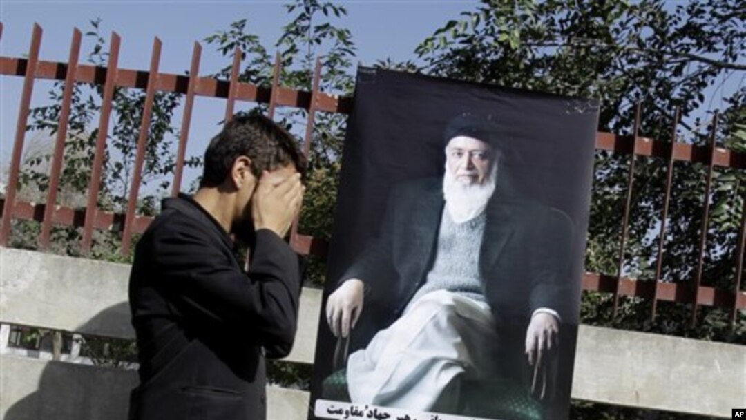 A supporter of Burhanuddin Rabbani walks a poster of the former Afghan President and head of the government's peace council during a rally in Kabul, Afghanistan, September 21, 2011 after he was killed by a blast the previous day.