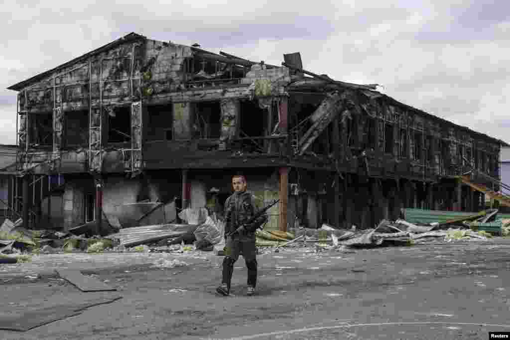 A pro-Russian rebel walks in front of a factory destroyed during a recent attack, in the town of Nizhnaya Krinka, eastern Ukraine. 