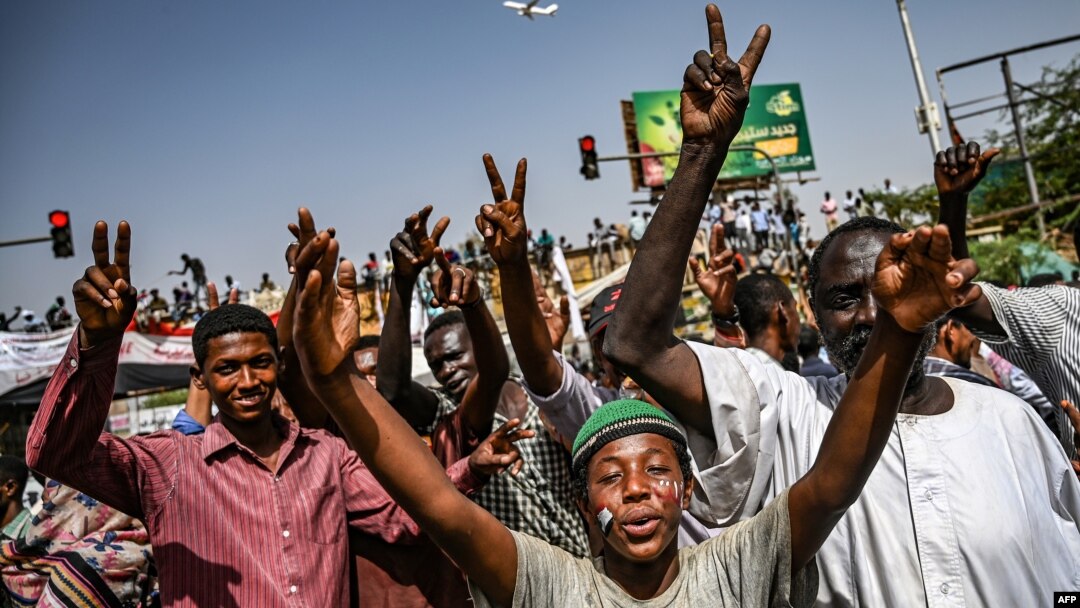 Sudanese protesters chant slogans and flash victory signs as they continue to demonstrate outside the army complex in Khartoum, April 17, 2019. They hardened their demand that the military men in power quickly step down.