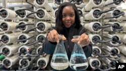 Lakeisha Bryant, public information representative at the Santa Clara Valley Water District, holds flasks of water before and after it is purified at the Silicon Valley Advance Purification Center on December 13, 2023, in San Jose, California. (AP Photo/Terry Chea)