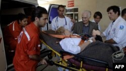 FILE - Lebanese-French Evelyne Ghandour, who suffers from heart problems, talks with her husband Georges, as workers of the International Committee of the Red Cross carry her into an ambulance at a hospital in Beirut.