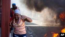 Una mujer pasa corriendo junto a barricadas de neumáticos ardiendo durante una nueva protesta para exigir cómo se gastaron los fondos de Petro Caribe en Haití.