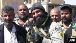 Ayyub Faleh al-Rubaie (center), known as Abu Azrael, poses with Shiite fighters at the Speicher military base, near the northern Iraqi city of Tikrit, on March 14, 2015.