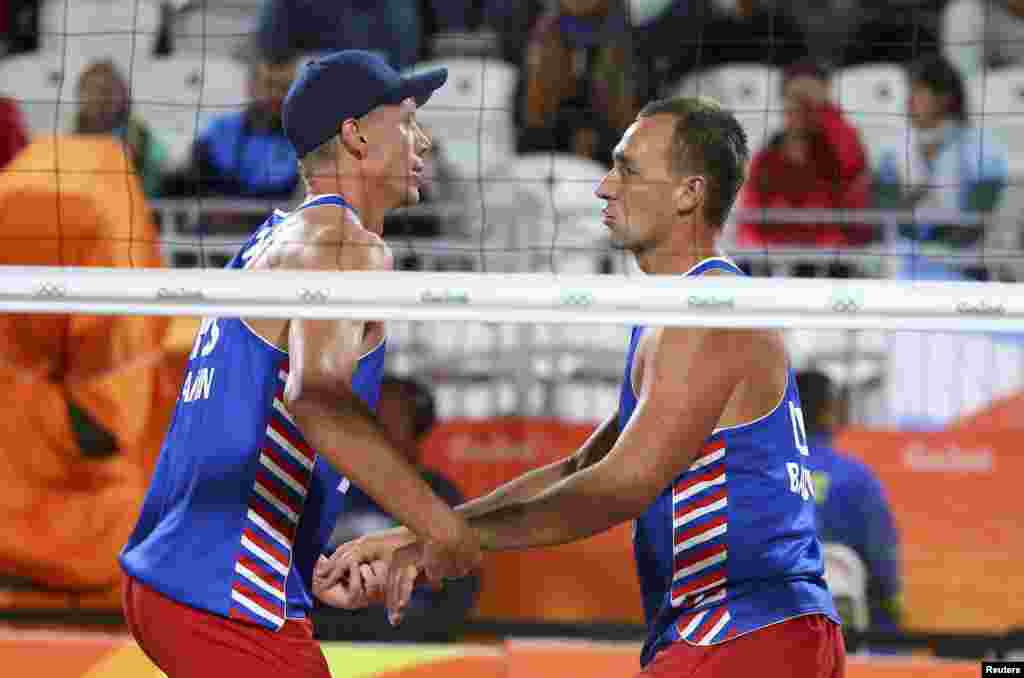 Pemain bola voli pantai Nikita Liamin dan Dmitri Barsouk dari Rusia merayakan kemenangan mereka atas Jerman (10/8). (Reuters/Ruben Sprich)