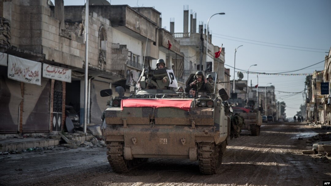 Turkish army vehicles drive on a street in Kobani, Syria, during an operation to relieve the garrison guarding the Suleyman Shah mausoleum in northern Syria, Feb, 22, 2015, 