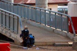 FILE - A woman rests on a footbridge, as Ghana enforces partial lockdown in the cities of Accra and Kumasi to slow the spread of the coronavirus disease (COVID-19) in Madina neighborhood of Accra, March 31, 2020.