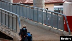 A woman rests on a footbridge, as Ghana enforces partial lockdown in the cities of Accra and Kumasi to slow the spread of the coronavirus disease (COVID-19) in Madina neighborhood of Accra, March 31, 2020. 