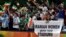 FILE - Fans cheer and wave the flag of Iran as Darya Safai (R) holds a large sign protesting the fact that women have not been allowed to attend volleyball matches in Iran.