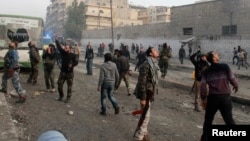 Civilians and Free Syrian Army fighters look into the sky at a site hit by what activists said are barrel bombs dropped by government forces in Aleppo on November 28, 2013.