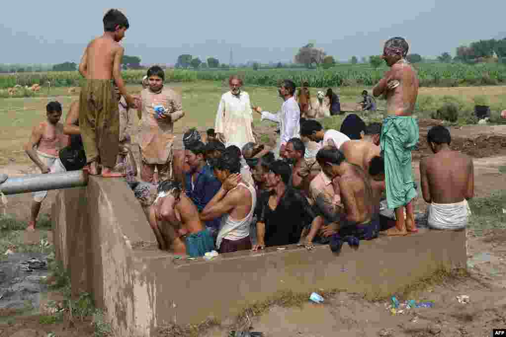 Farmers and vendors take bath at a cattle market set to buy sacrificial animals ahead of Eid al-Adha Muslim festival or the &#39;Festival of sacrifice&#39; in Lahore on July 26, 2020. - Eid al-Adha, feast of the sacrifice, marks the end of the Hajj pilgrimage to…