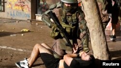 A policeman detains a demonstrator during a protest against Chile's government in Santiago, Chile, Nov. 13, 2019.