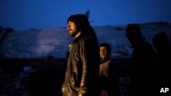 Syrian people seen near a damaged building after it was attacked by a Syrian Army Jet in Azaz, Syria, Sunday, Dec 16, 2012.