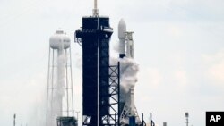 A SpaceX Falcon 9 rocket with a payload of approximately 60 satellites for SpaceX's Starlink broadband network stands pad 39A moments before the launch was scrubbed due to weather concerns at the Kennedy Space Center in Florida, Sept. 28, 2020.