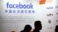 FILE - Visitors walk past the Facebook logo at an exhibitor's display at the Global Mobile Internet Conference (GMIC) in Beijing, April 26, 2018.